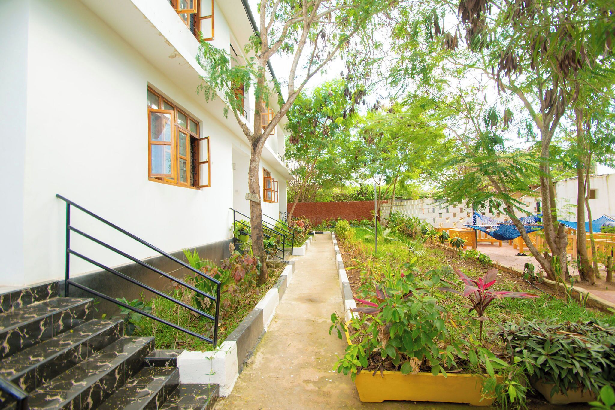 Un edificio con escaleras, un camino y un jardín con diversas plantas.