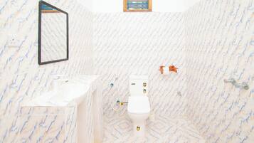 A bathroom with a marble floor, a toilet, a sink, and a shower.