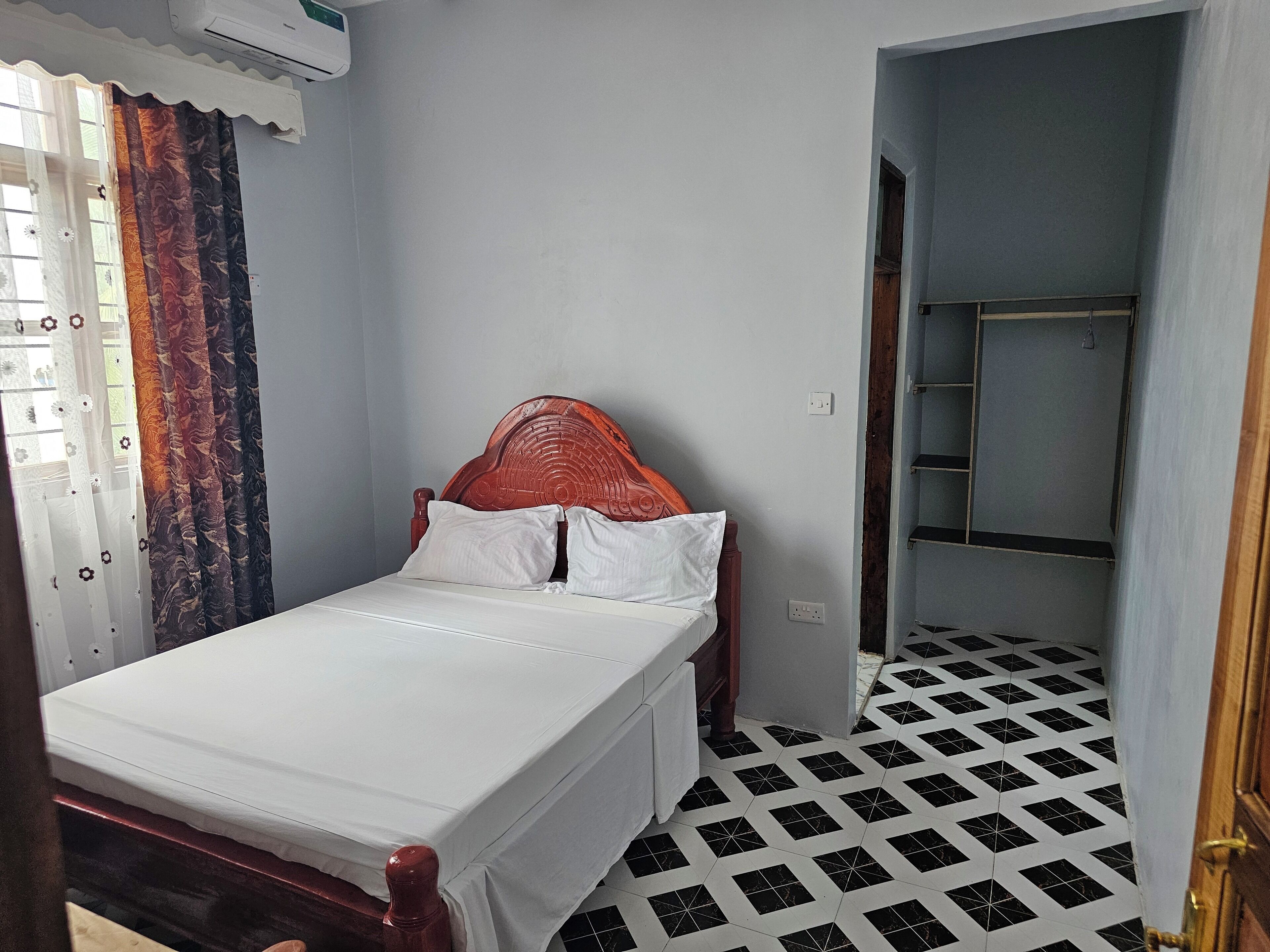 A bedroom with a single bed, a wooden headboard, and a patterned floor.