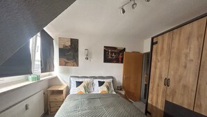 Een slaapkamer met een bed, een kast, een nachtkastje, een raam en een radiator.