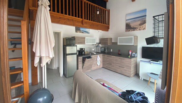 Une cuisine compacte dotée d’appareils électroménagers modernes, un coin repas avec un canapé et un balcon agrémenté de balustrades en bois.
