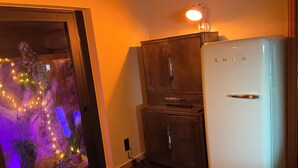A kitchen with a white refrigerator, wooden cabinets, and a glass door with a decorative plant inside.