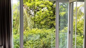 A bedroom with a large sliding glass door leading to a lush garden.