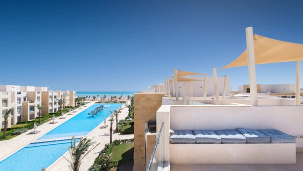 Ein Hotel mit Pool, Außenbereich und Blick auf den Strand.