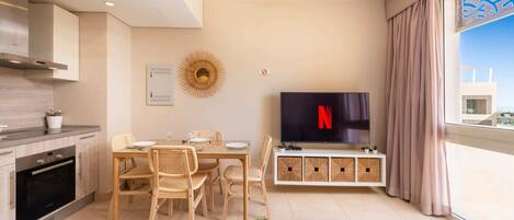 A modern living room with a dining area, a kitchen, and a large window with a view.