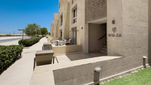 Una entrada de hotel moderna con un camino despejado, asientos al aire libre y una escalera que conduce a la entrada.