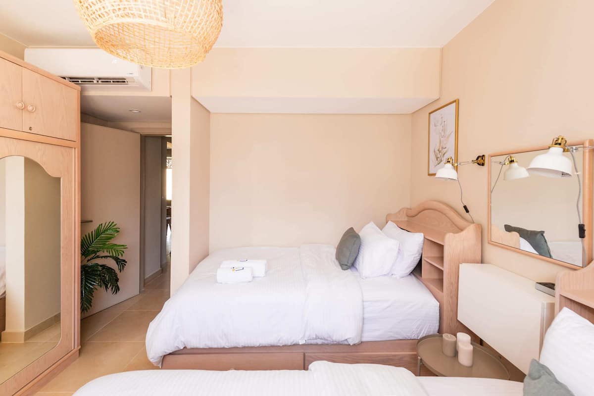 A bedroom with a bed, bedside table, mirror, and a hanging light fixture.