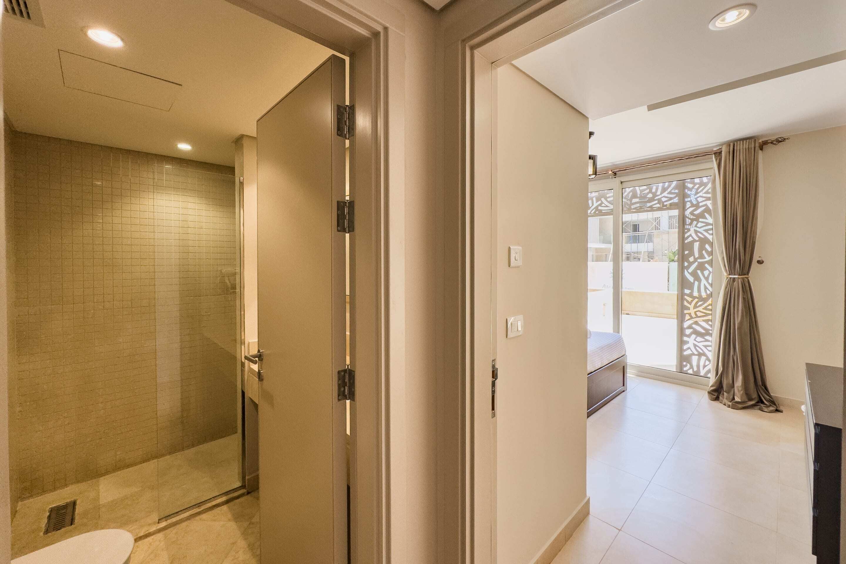 A hotel room with a shower, a bed, and a balcony with a view.