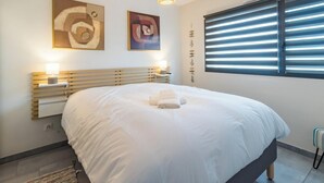 A hotel room with a large bed, two wall-mounted lamps, and artwork above the bed. - "L'escale du Goelo" in Paimpol, close to beaches (Paimpol)