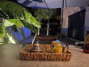 A table with a woven basket containing a decorative pot, a honey jar, and a candle. - Contemporary house (Boisseron)