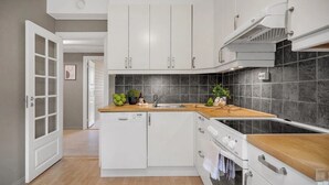 A modern kitchen with white cabinets, a built-in oven, and a wooden countertop.