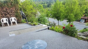 A rooftop terrace with a circular seating area, two white chairs, and a statue.