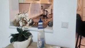 A kitchen with a window, a potted plant, a decorative lighthouse, and a plate of snacks.
