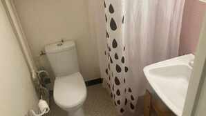 Une petite salle de bain avec des toilettes, un rideau de douche à motifs à pois et un lavabo.