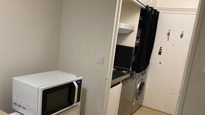 Une petite cuisine équipée d’un four à micro-ondes, d’un petit four et d’un lave-linge.