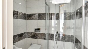 A modern bathroom with a glass-enclosed shower, white tiles, and marble accents. - Lamira Pansion (Fethiye)