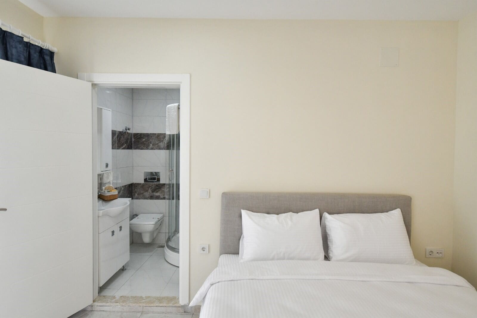 A bedroom with a bed, a bedside table, and a bathroom visible through an open door.