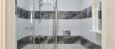 A modern bathroom with a glass-enclosed shower, a toilet, and a sink.