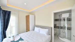 A hotel room with a bed, a wardrobe, a shower, and a window with curtains. - Lamira Pansion (Fethiye)