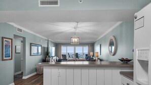 A spacious kitchen with a central island, a dining area with chairs, and a view to the outside. - Sandy Key 213:  2 BR/2 BA Perdido Key Beachfront Condo & Pools, On-Site Rental Office, Sleeps 6 (Pensacola)