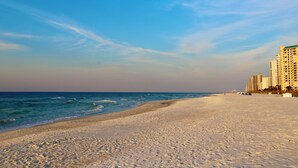 A beach with a clear sky, a sandy shore, and tall buildings in the background. - Sandy Key 213:  2 BR/2 BA Perdido Key Beachfront Condo & Pools, On-Site Rental Office, Sleeps 6 (Pensacola)