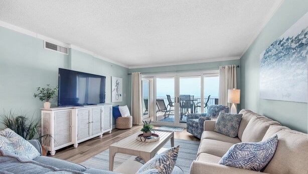 A living room with a television, sofa, and a view of the balcony. - Sandy Key 213:  2 BR/2 BA Perdido Key Beachfront Condo & Pools, On-Site Rental Office, Sleeps 6 (Pensacola)