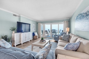 A living room with a television, sofa, and a view of the balcony. - Sandy Key 213: 2 BR/2 BA Perdido Key Beachfront Condo & Pools, On-Site Rental Office, Sleeps 6 (Pensacola)