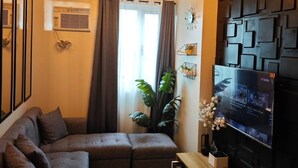 Una sala de estar moderna con un sofá modular, un televisor montado y un panel decorativo en la pared.