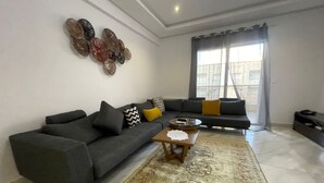 Un salon avec un canapé gris, une table basse et un tapis à motifs.