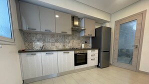 Une cuisine moderne avec des meubles de couleur bois clair, un four encastré et un réfrigérateur en acier inoxydable.