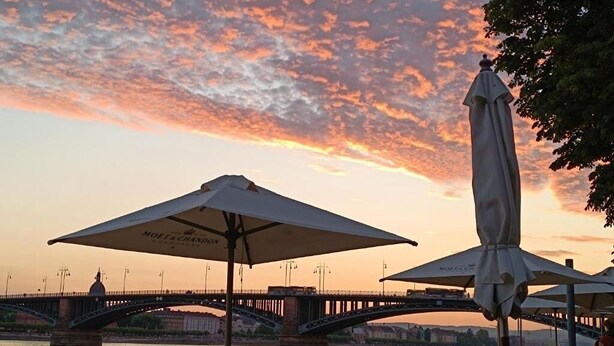 Een zonsondergang met een brug en parasols.