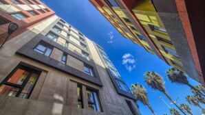 A modern building with multiple floors, large windows, and a clear sky. - Apartment by Playa de Las Canteras Beach (Las Palmas de Gran Canaria)