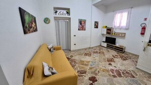 Una sala de estar con un sofá amarillo, un televisor y un suelo con estampado de piedra.