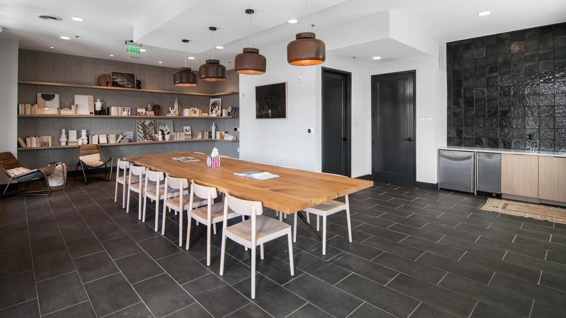 Une salle de réunion moderne, dotée d’une longue table en bois, de chaises blanches et d’un éclairage suspendu.