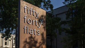 Une enseigne pour le complexe d’appartements « Fifty Forty Flats », avec un design moderne et un arbre en arrière-plan.