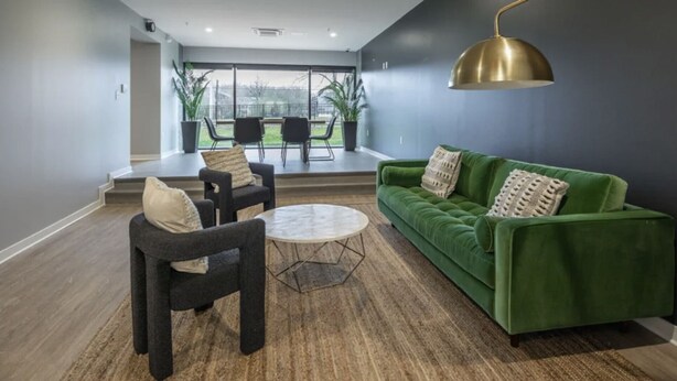 Un salon moderne avec un canapé vert, deux fauteuils et une table basse.