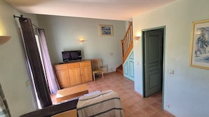 A room with a wooden desk, a television, a cabinet, a staircase, and two doors. - Vacation residence with garden and 2 swimming pools. Ideal for summer vacations. (Tourrettes)