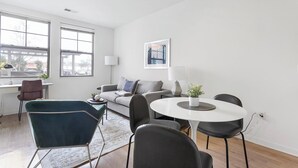 A modern living room with a sofa, a round dining table, and a blue armchair.