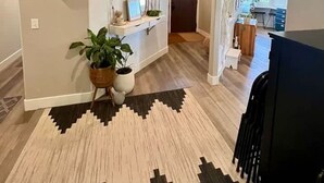 A spacious hallway with a patterned rug, a potted plant, and a mirror on the wall. - Black Hills Getaway With Hot Tub Game Room for 18 (Spearfish)