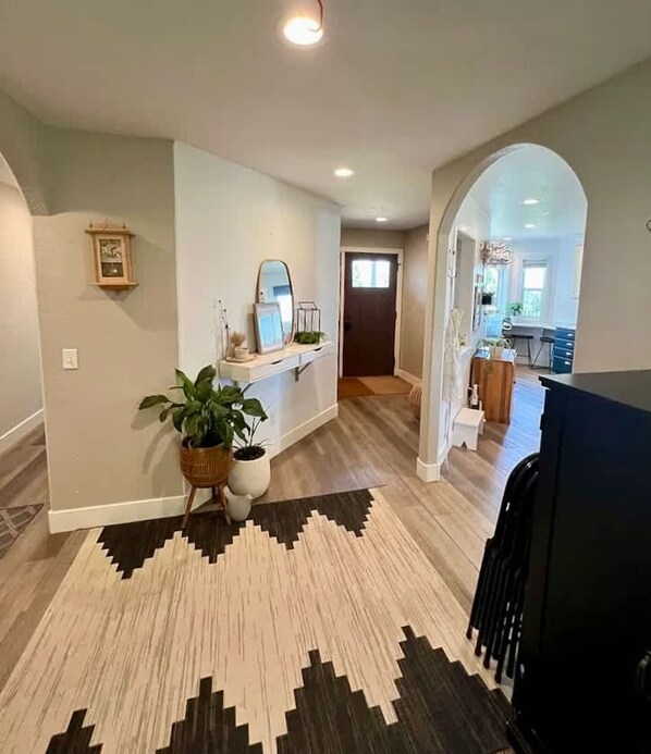 A spacious hallway with a patterned rug, a potted plant, and a mirror on the wall. - Black Hills Getaway With Hot Tub Game Room for 18 (Spearfish)