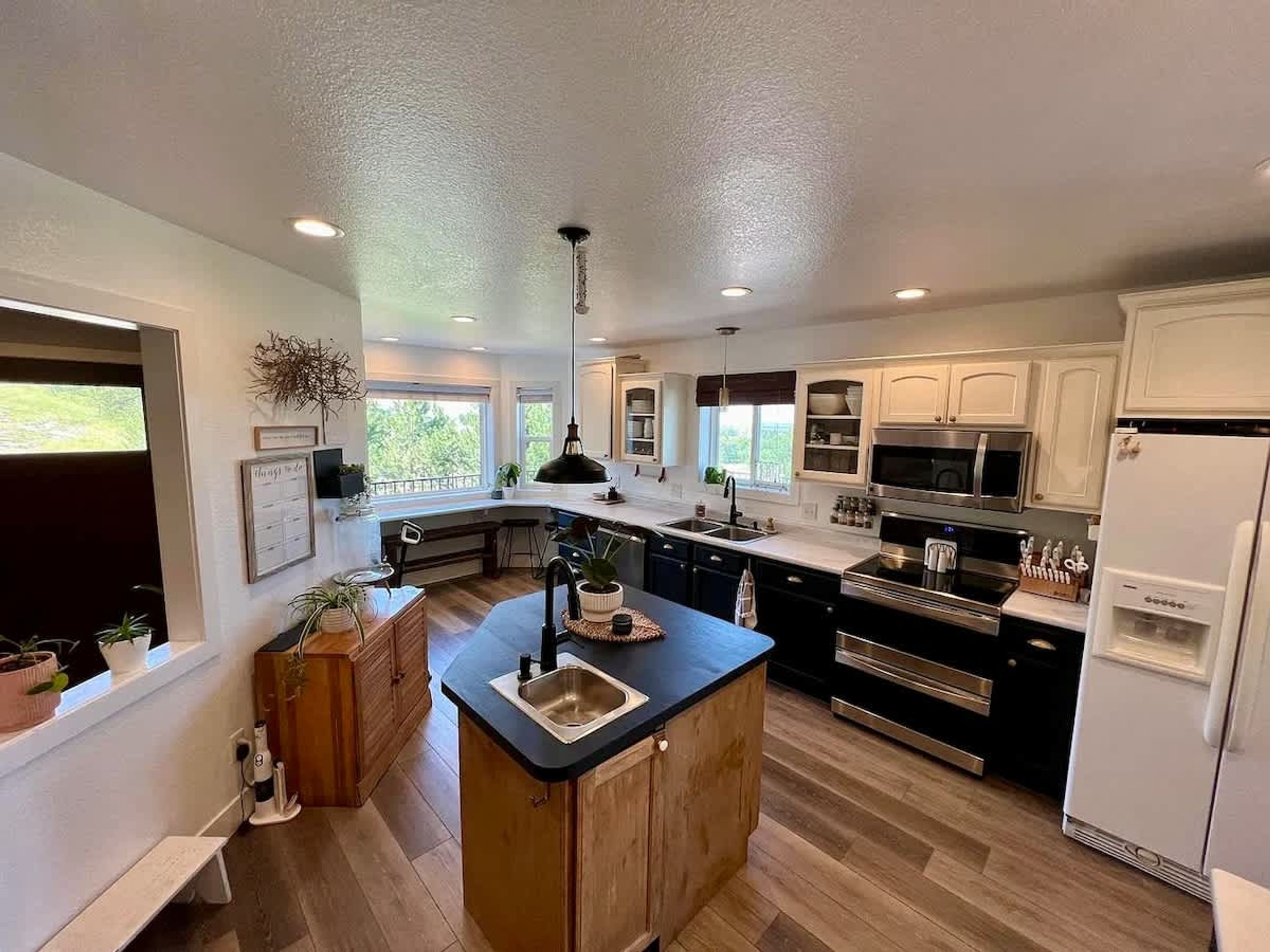A modern kitchen with a central island, stainless steel appliances, and a view of the outdoors.