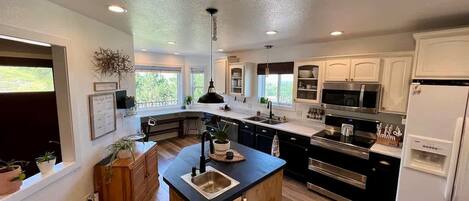 A modern kitchen with a central island, stainless steel appliances, and a view of the outdoors.