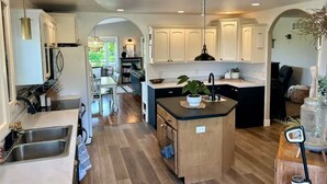 A modern kitchen with wooden flooring, white cabinetry, and a central island. - Black Hills Getaway With Hot Tub Game Room for 18 (Spearfish)