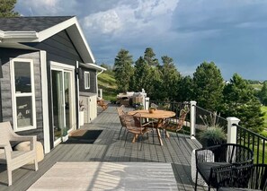 Eine Terrasse mit einem runden Tisch und Stühlen, einem Whirlpool und Blick auf eine bewaldete Gegend.