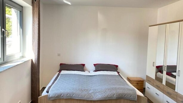 Une chambre à coucher avec un lit, une armoire et une fenêtre.