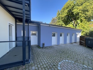A building with a blue exterior, a wooden deck, and a paved courtyard.