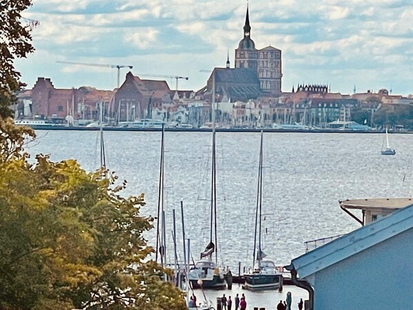 A waterfront view with boats, a prominent building with a spire, and a cityscape in the background.