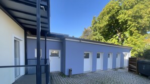 Rakennuksessa on sininen julkisivu, puinen terassi ja kivetty sisäpiha.