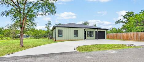 A single-story house with a garage, a driveway, and a wooden fence.