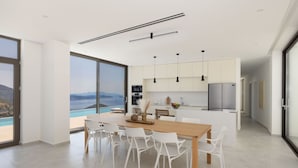 Una cocina moderna con una isla grande, sillas blancas e iluminación colgante.